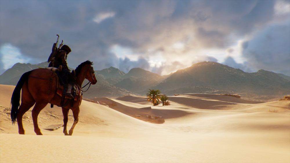 Assassin's Creed Origins Bayek riding through the Egyptian desert at sunset
